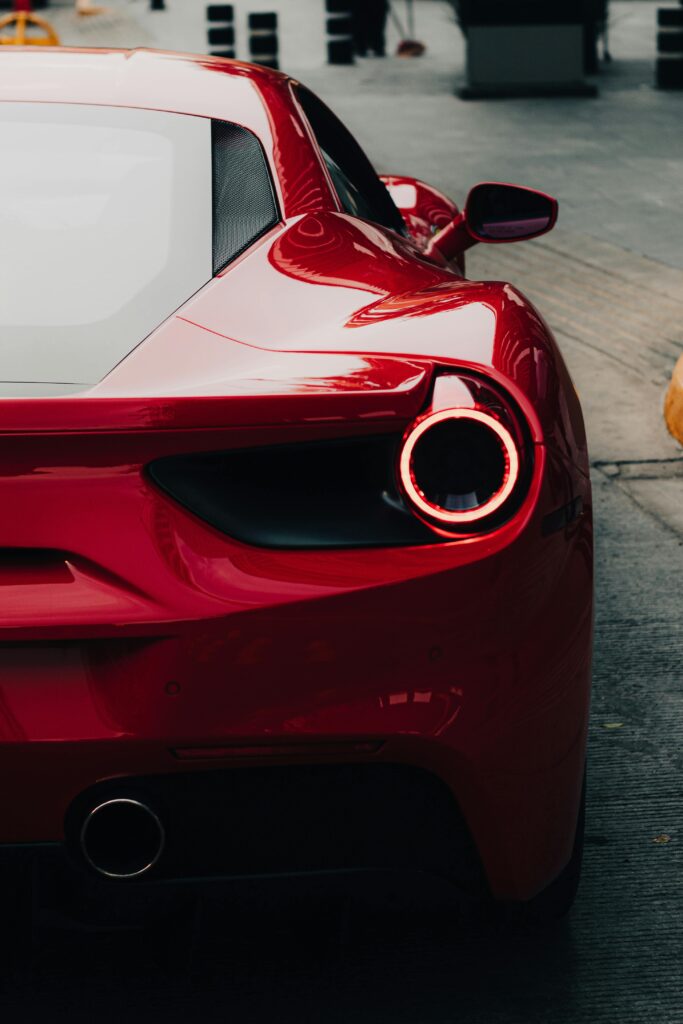 Sleek red Ferrari 458 viewed from the back on a city street, showcasing luxury and speed.