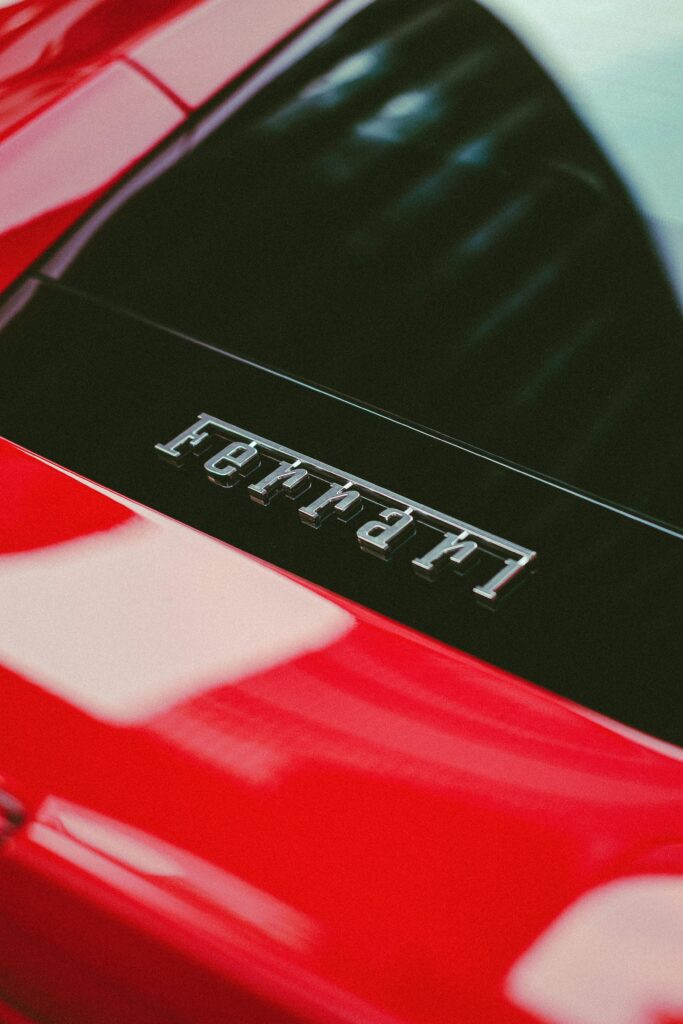 Detailed view of a Ferrari logo on a vibrant red supercar, exuding luxury and prestige.