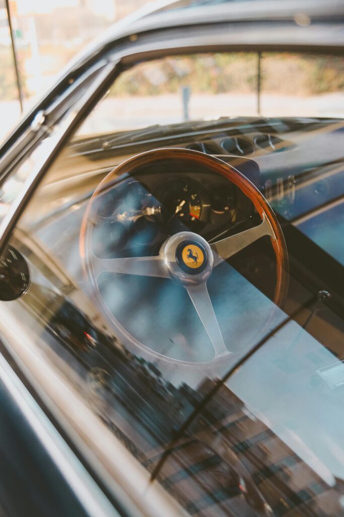 Elegant interior of a classic Ferrari car showcasing a wooden steering wheel with smooth reflections.