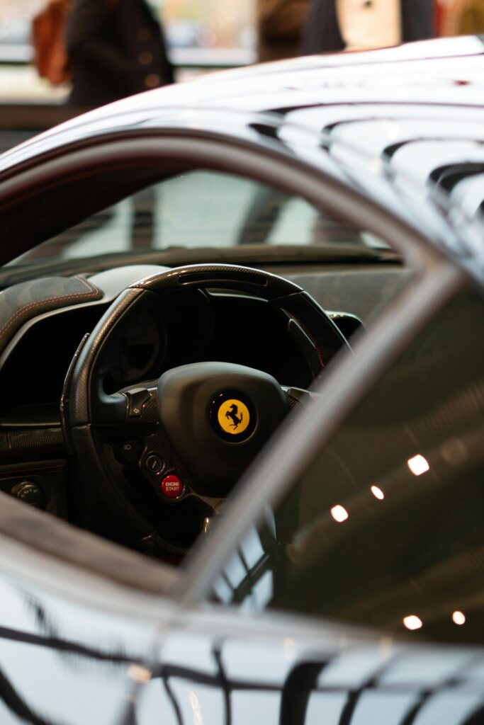 Detailed view of a Ferrari steering wheel inside a showroom, showcasing luxury car design.